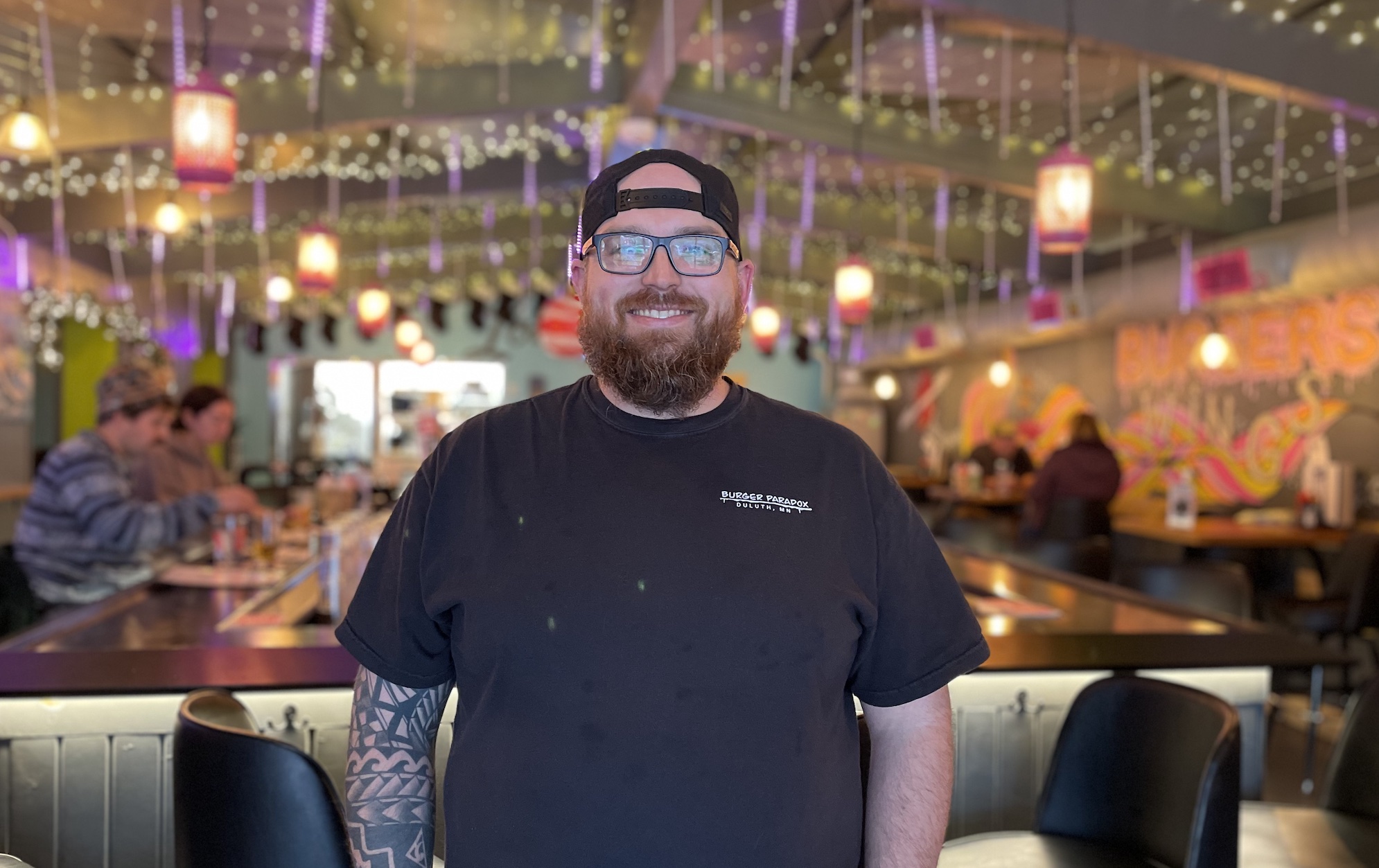 Dan Lefebvre standing in the colorful bar setting at Burger Paradox